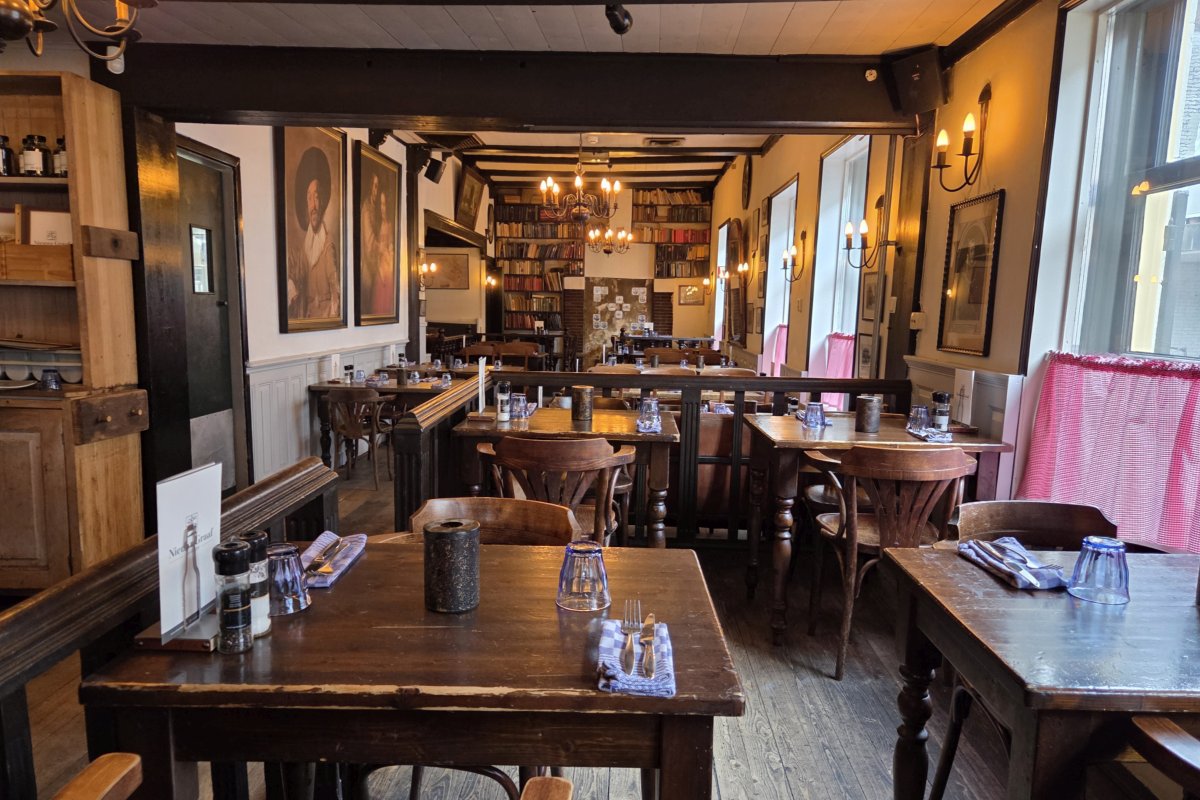 Interieur van restaurant De Nieuwe Graaf in Hilversum met houten meubels, warme verlichting en een gezellige, huiselijke sfeer.<br />
